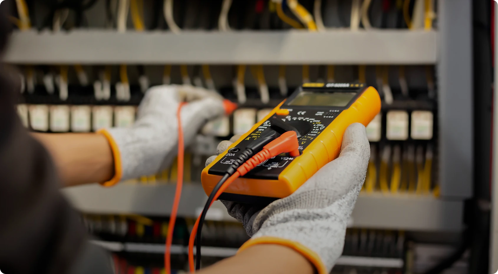 Electrician using multimeter on circuit board
